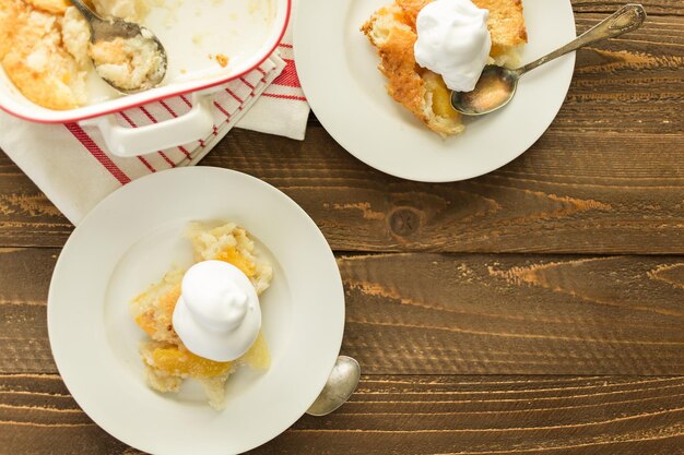 Freshly baked peach cobbler with scoop of whipped cream.