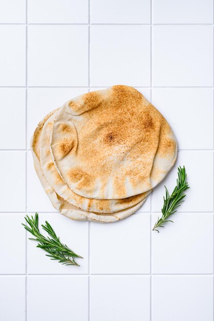 Freshly baked pita bread set on white ceramic squared tile table background top view flat lay with copy space for text