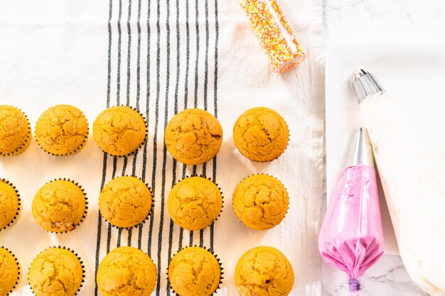 Photo freshly baked pumpkin spice cupcake cooling on kitchen towel.