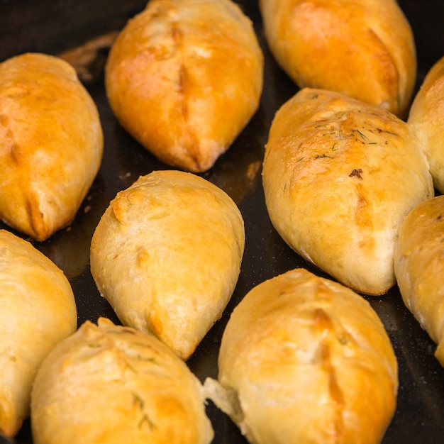 freshly baked ruddy patties lying on a black steel baking tray Closeup view