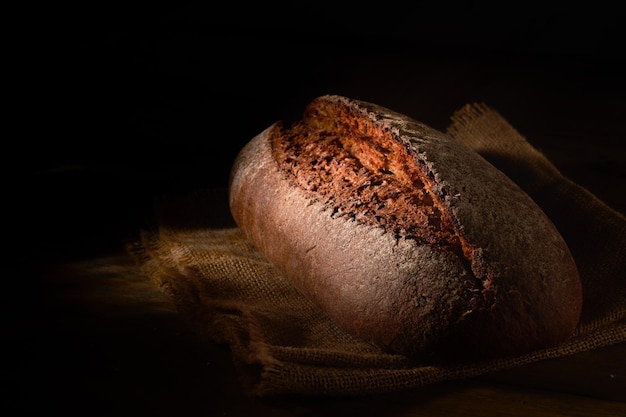 Photo freshly baked rye bread on wooden board wooden background
