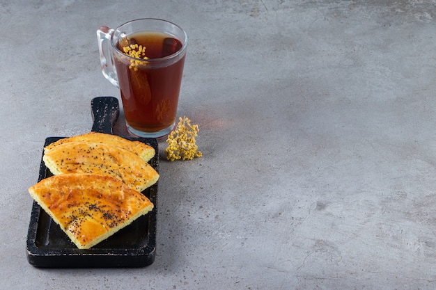 Freshly baked sliced flat bread with black seeds with a glass cup of herbal tea