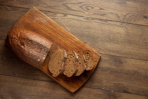 freshly baked sliced rye bread on a wooden cutting board, flat lay, copy space