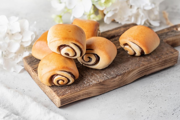 白い春の花で木の板に朝食の焼きたての甘いシナモン ロール テキスト領域を持つイースターの伝統的な菓子食品