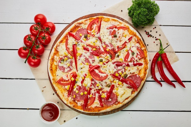 Freshly baked tasty pepperoni pizza with salami mozzarella cheese corn and pepper served on wooden background with tomatoes sauce and herbs Food delivery concept Restaurant menu