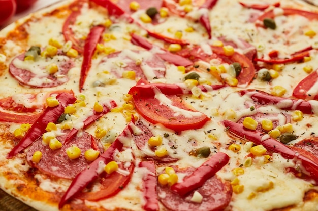 Свежеиспеченная вкусная пицца пепперони с салями, сыром моцарелла, кукурузой и перцем, подается на деревянном фоне с томатным соусом и зеленью Концепция доставки еды Меню ресторана