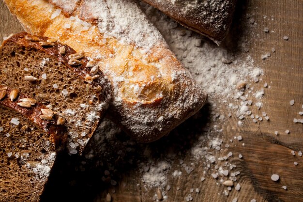 木製のテーブルに小麦粉と小麦粉と焼きたての伝統的なパン小麦粉と新鮮なバゲット
