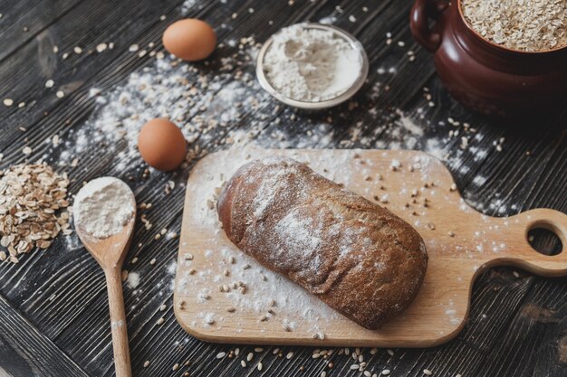 Photo freshly baked traditional bread on wooden table. dark moody background with free text space.