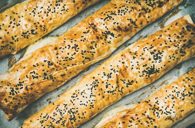 Freshly baked Turkish borek pastry rolls with spinach top view