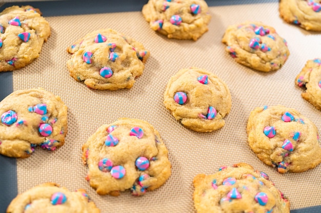 Freshly baked unicorn chocolate chip cookies on a baking sheet lined with a silicone mat.