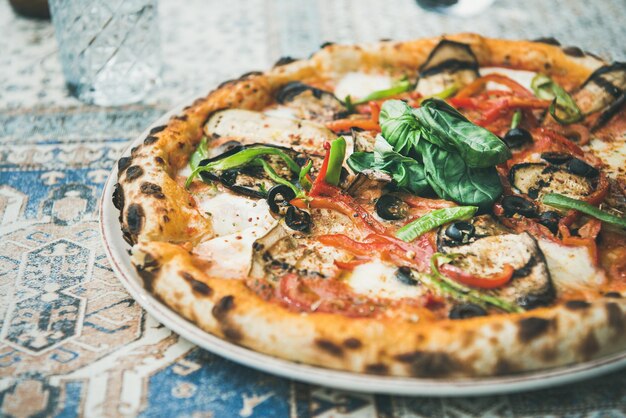 Photo freshly baked vegetarian pizza with basil over oriental tile background
