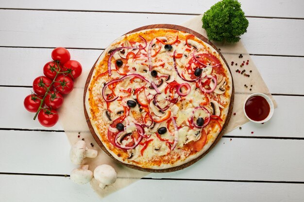 freshly baked vegetarian pizza with tomatoes mushrooms red pepper olives onion and mozzarella served on wooden background with sauces and herbs food delivery concept restaurant menu