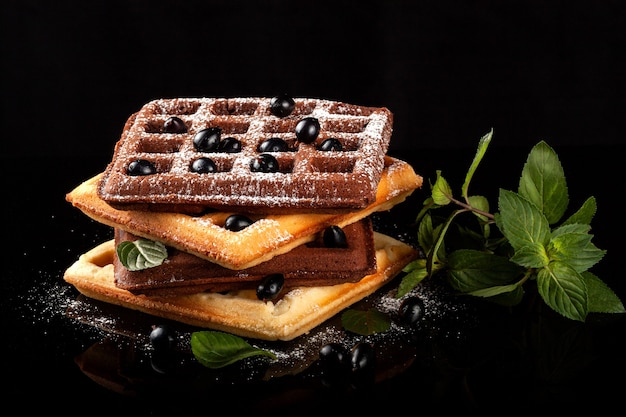 Freshly baked Viennese waffles lie on a black table.