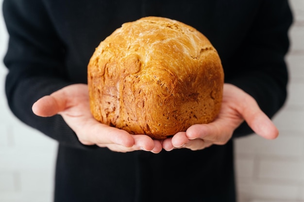 Freshly baked wheat bread in baker's hands closeup