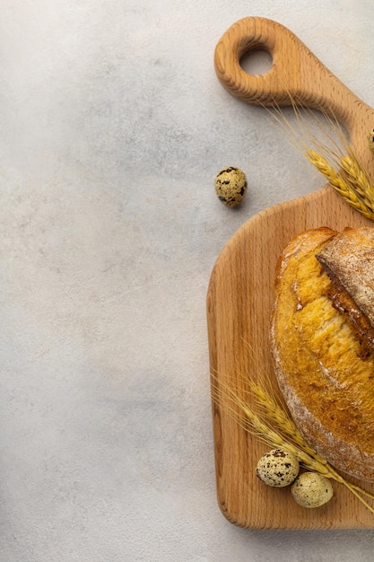 Freshly baked wheat loaf bread on a wooden board on a light background