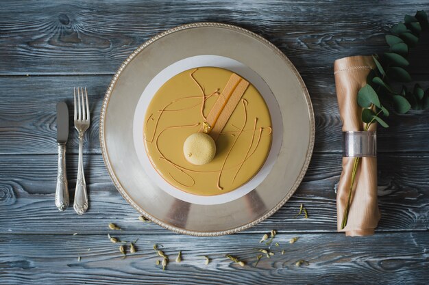 Torta di budino gialla appena sfornata con dacquoise di mandorle, confit di lampone, strato croccante con nocciole caramellate e polvere di lamponi