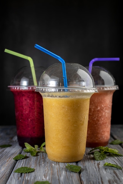 Freshly blended fruit smoothies of various colors and tastes in plastic glass jars