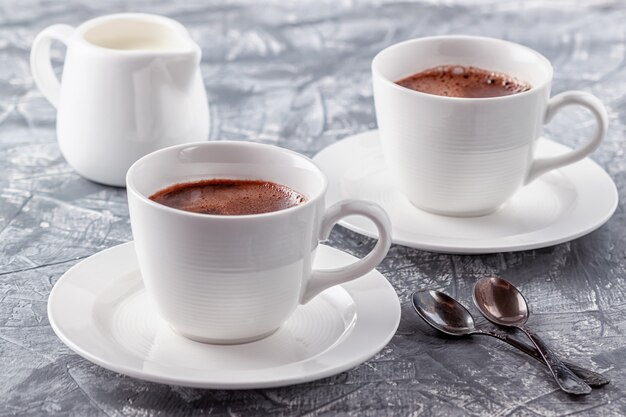 Freshly brewed aromatic coffee with cream on a gray