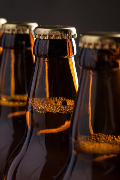 Бутылки свежесваренного пива в ряд над серой бетонной стеной