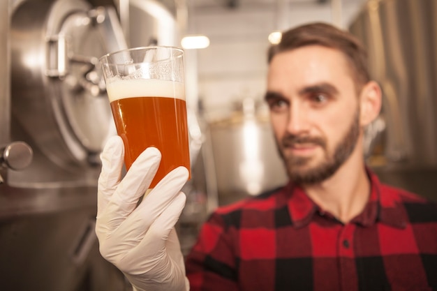 Foto birra appena prodotta nel birraio professionista di vetro sta tenendo