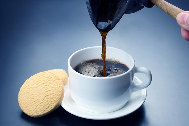 Foto caffè nero appena preparato dai turchi versato in una tazza bianca. bevanda calda