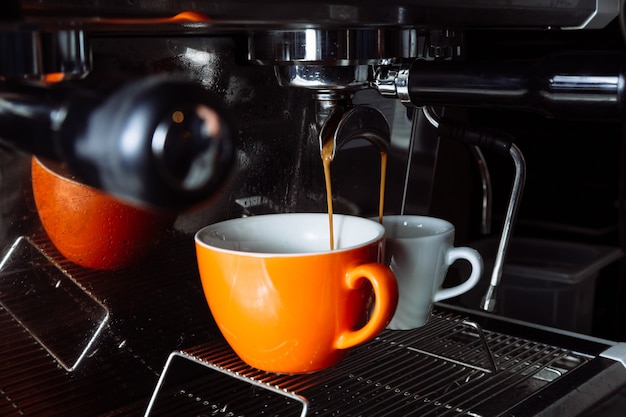 Freshly brewed coffee is poured from the coffee machine into cups pouring beverage