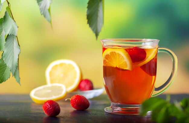 Freshly brewed tea with lemon and strawberries in a large glass cup