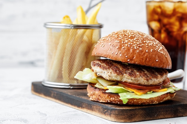 Freshly cooked burger on wooden board on light background