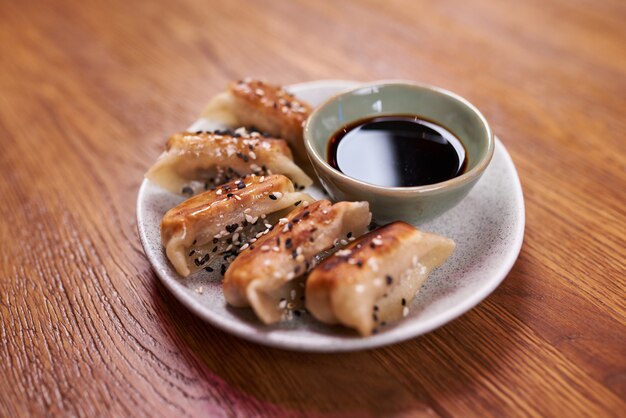 Freshly cooked dumplings gedza with soy sauce. On wooden background