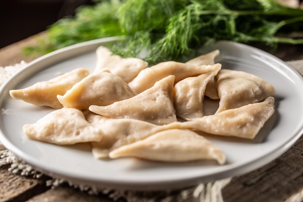 Freshly cooked pierogi or vareniki dumplings with filling but without a topping served on a plate.