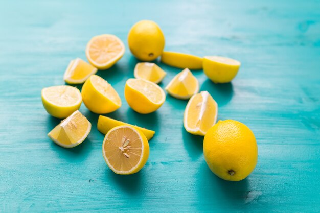 Photo freshly cut half and whole lemons on rustic aquamarine colour boards. summer, vitamins and freshness concept.