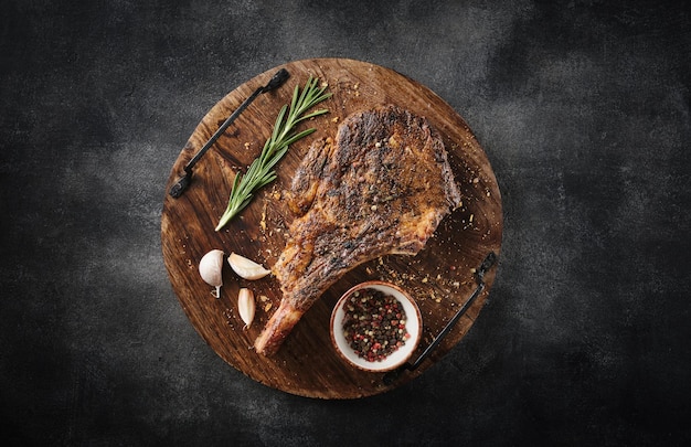 Photo freshly grilled tomahawk steak on a wooden cutting board bbq food top view grey background