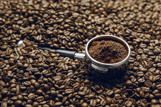 Freshly Ground Coffee in Portafilter on Roasted Coffee Beans Close Up