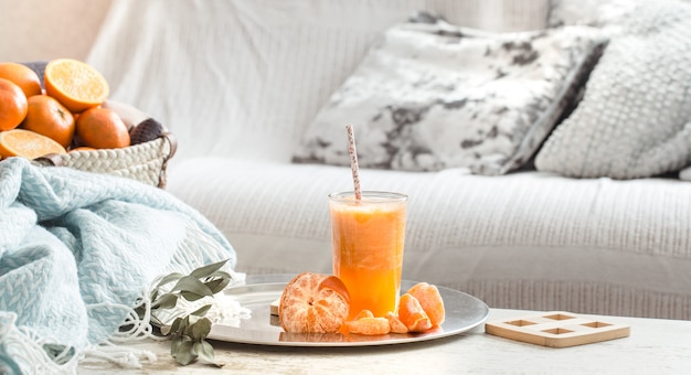 Freshly-grown organic fresh orange juice in the interior of the house, with a turquoise blanket and a basket of fruit