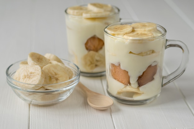 Freshly made banana pudding in the circles and the slices of banana on a white table.