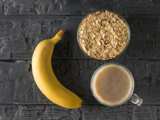 Freshly made banana smoothie, banana and bowl of oatmeal on the table