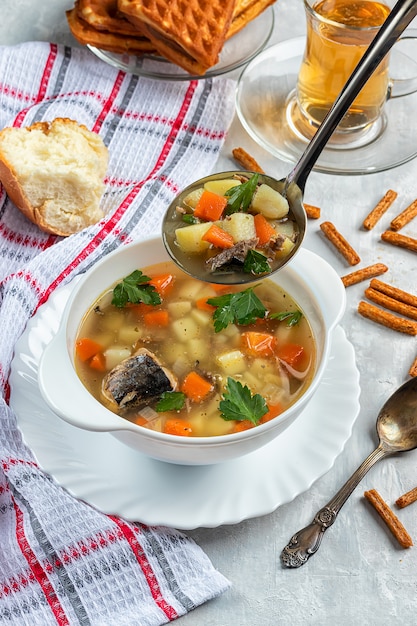 Freshly made canned tuna soup with crackers on concrete background with soup ladle