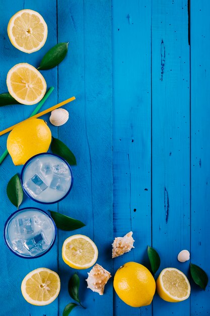 Freshly made lemonade with ice on a blue wooden table on the beach