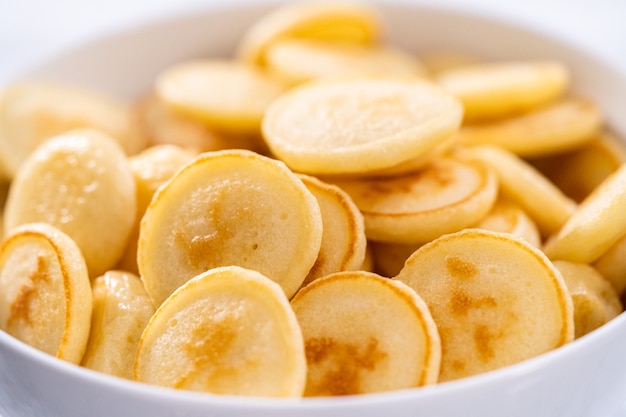 Freshly made mini pancake cereal in a white bowl.