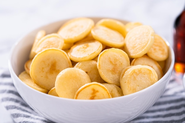 Freshly made mini pancake cereal in a white bowl.