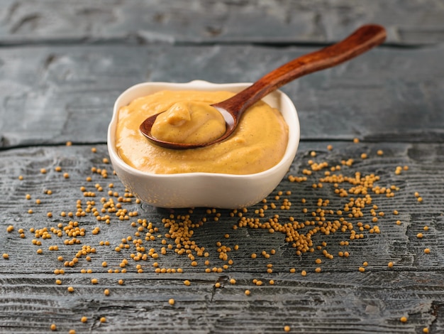 Photo freshly made mustard sauce and seeds on a wooden table