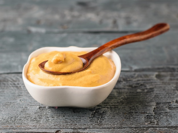 Freshly made mustard seed sauce in a white bowl on a rustic table with a spoon