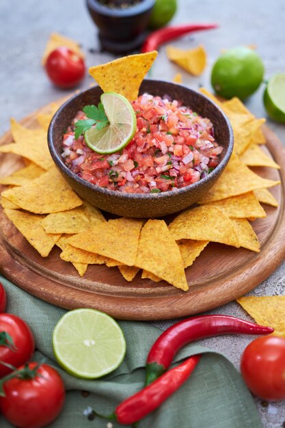 Freshly made salsa dip sauce with nacho chips on wooden board