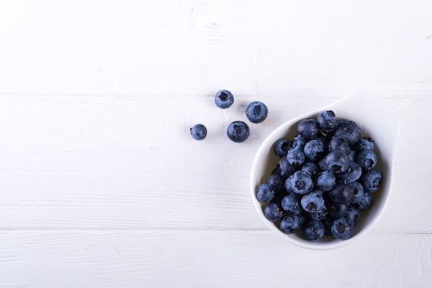 Freshly picked blueberries in bowl on white wood