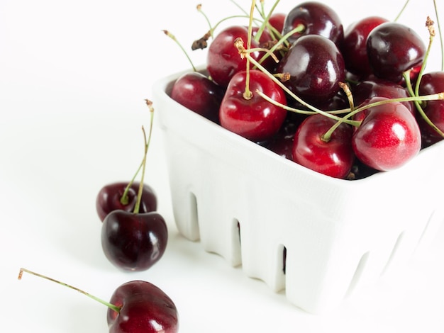 Freshly picked heap of cherries in white basket.