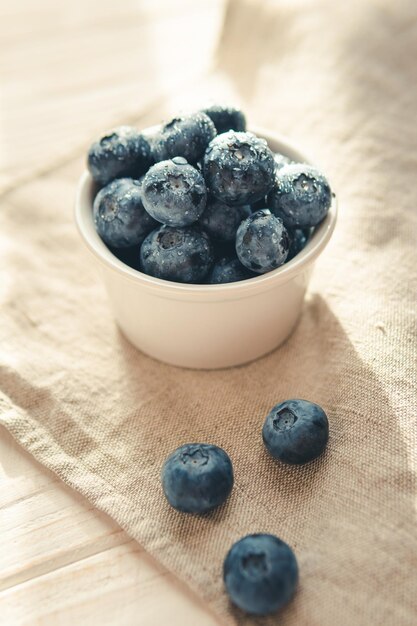 Freshly picked juicy blueberries in the bowl on wooden background close up Blueberries background