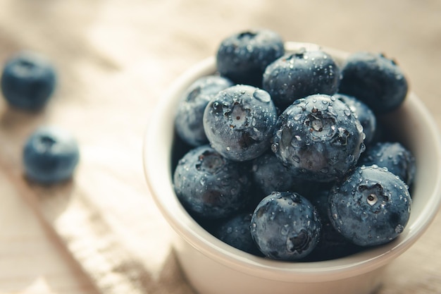 Freshly picked juicy blueberries in the bowl on wooden background close up Blueberries background