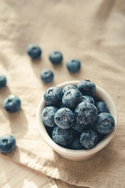 Freshly picked juicy blueberries in the bowl on wooden background close up Blueberries background