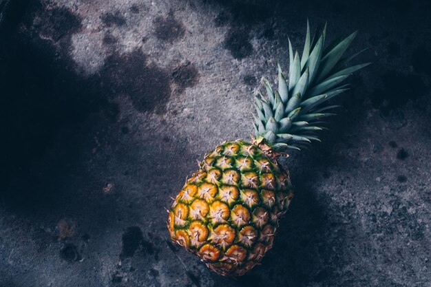 Freshly picked organic pineapple fruit on dark concrete ground or background