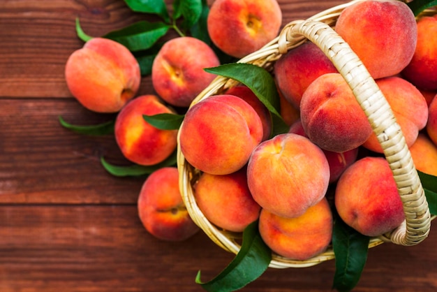 Freshly picked peaches in basket on a brown wooden background